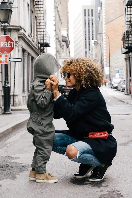 Adult kneeling to comfort a child on a city street